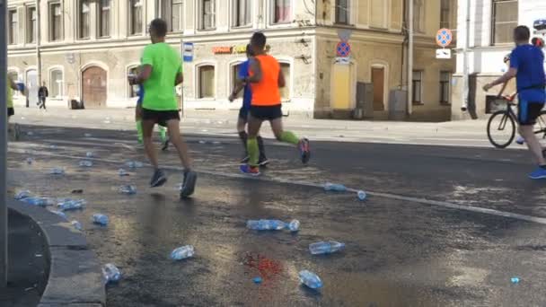 30 июня 2019 Санкт-Петербург: Люди бегут марафон и бросают пластиковые бутылки с водой на асфальт в замедленной съемке — стоковое видео