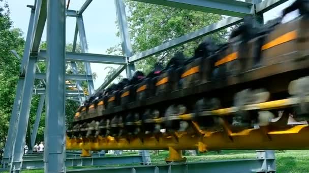Ludzie jechać wzdłuż żółtych szyn Roller Coaster w pobliżu ziemi — Wideo stockowe