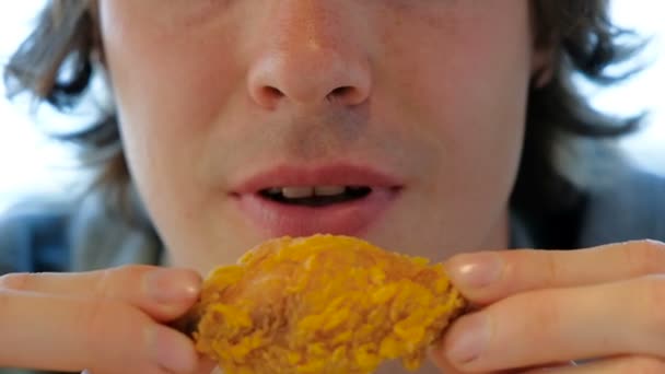 Typ mit schwarzem Lockenhaar hält Junk-Chicken-Scheibe in Händen — Stockvideo