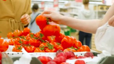 genç kadın beyaz plastik torba tutar ve domates seçer