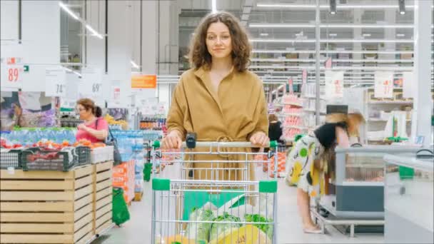 Gadis cantik dengan rambut ikal longgar berdiri dengan keranjang belanja — Stok Video