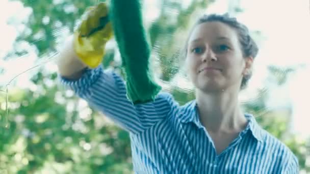 Jonge vrouw loopt groene natte spons zuigmond op vuile venster — Stockvideo
