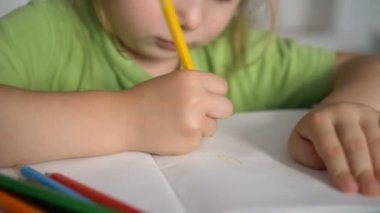 küçük kız sarı kalem ile beyaz kağıt levha üzerine çizer