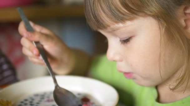 年轻的漂亮女孩捕捉浆果在牛奶与金属勺 — 图库视频影像