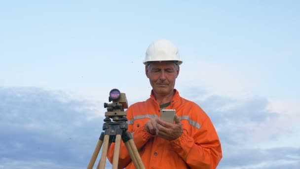 Explorer in orange types on smartphone by geodetic device — Stock Video