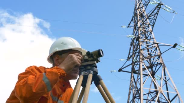 Senior surveyor looks through level and types smiling — Stock Video