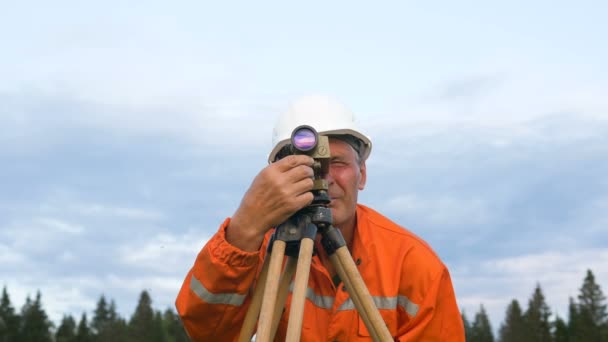 Geometra guarda attraverso teodolite manopola di messa a fuoco rotante — Video Stock