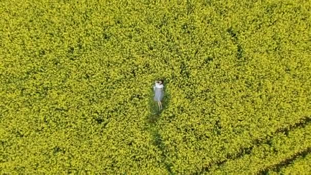 Pretty girl rests on blooming rapeseed field zoom in — Stock Video
