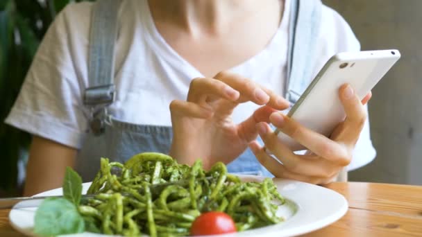 Jovem mulher em denim macacões tipos no smartphone moderno — Vídeo de Stock