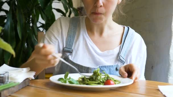 美しいブルネットは、緑の新鮮なサラダを食べ、口を拭きます — ストック動画