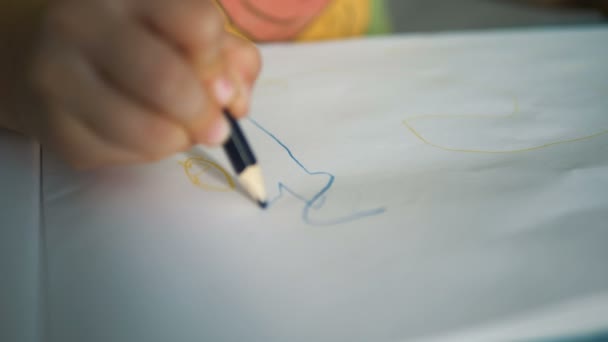 Маленькая рука ребенка рисует на белом листе бумаги карандашом — стоковое видео