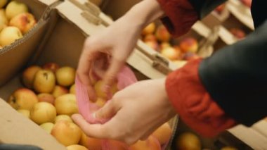 kız bir süpermarkette bir eko torbaya kayısı koyar