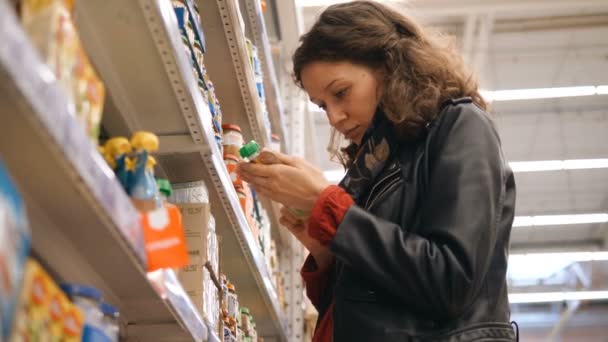 Jolie fille lit la composition des aliments pour bébés sur l'emballage dans le supermarché — Video