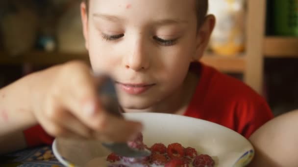 Kleiner Junge isst frische Himbeeren mit einem Milchlöffel Zeitlupe — Stockvideo