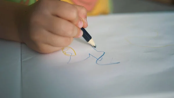 Piccola mano bambino disegna su foglio di carta bianca con la matita — Foto Stock