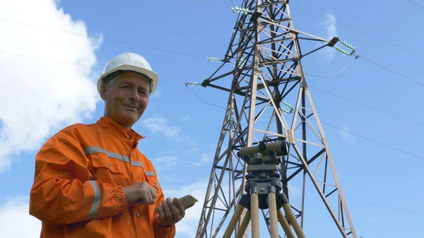 Topógrafo olha através theodolite e tipos no smartphone — Fotografia de Stock