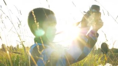 erkek siluet yeşil alanda oturan retro kamera tutar