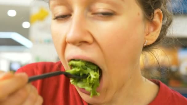 Ragazza dagli occhi grigi mangia insalata di lattuga con forchetta e sorrisi — Video Stock