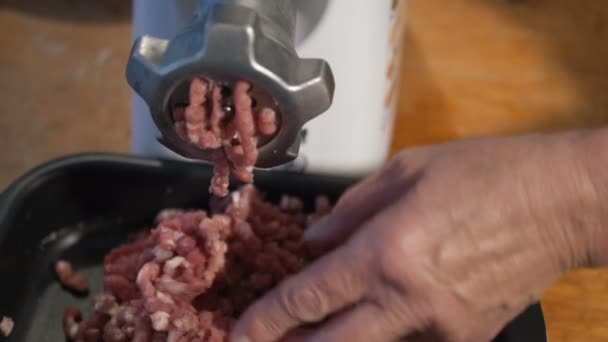 Persona reúne carne picada en un tazón negro bajo la picadora de carne — Vídeo de stock