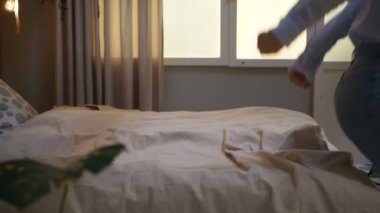Kız, açık renkli çarşaflarla yatakta zıplamaktan zevk alıyor.