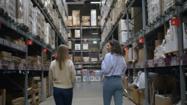 Meninas caminham ao longo do departamento apontando para mercadorias no hipermercado — Vídeo de Stock