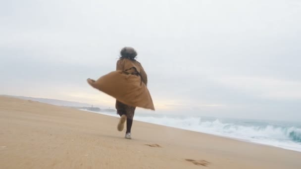 Aktiv flicka turist körs längs sandstrand mot oceanscape — Stockvideo