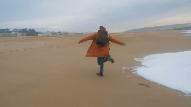正の男はビーチで回転する泡の海の波から走り — ストック動画