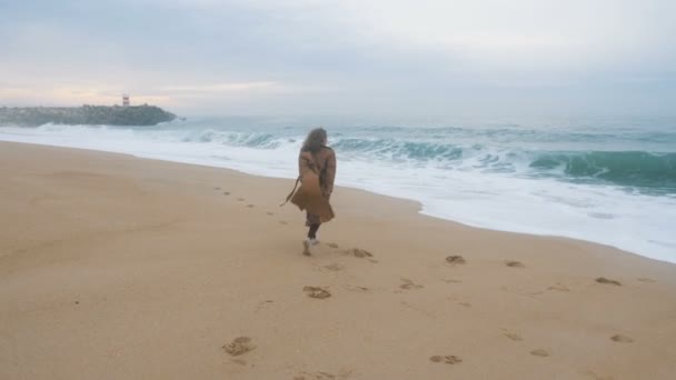 Woman runs jumping on sand beach and rejoicing against ocean — Stock Video