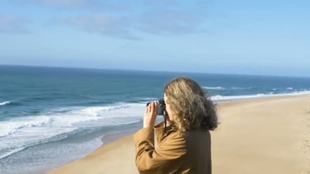 Mujer rizada toma fotos de océano impresionante usando la cámara — Vídeos de Stock