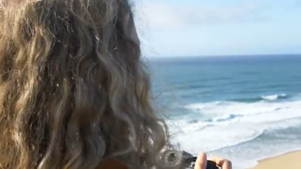 Gelukkig toerist neemt foto 's van geweldig oceaan wassen strand — Stockvideo