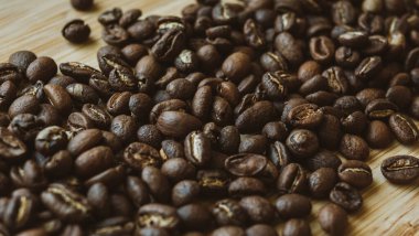 Taze kavrulmuş aromatik kahve çekirdekleri ahşap masaya saçılmış.