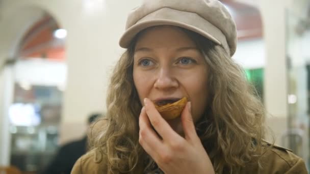 Mujer en un gorro de reportero comiendo postre tradicional portugués pastel de nata y bebiendo café en la cafetería cámara lenta — Vídeos de Stock