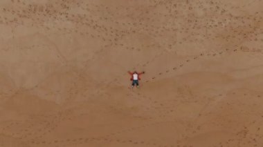 Rahatlamış adam, insan ayak izleriyle büyük bir kehribar plajında yatıyor.