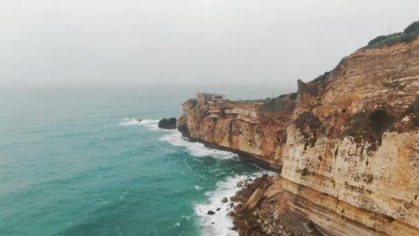 Rocky mountain towers above immense ocean washing coast — Stock Video