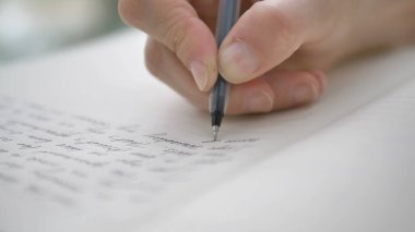 kişi ışık arkaplanındaki defter sayfasına metin yazar