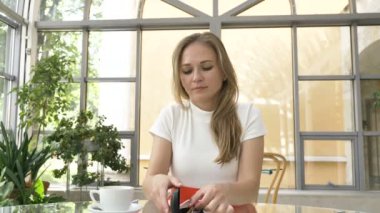 Genç bir kadın tablet üzerinde çalışırken çantadan gözlük çıkartıyor.