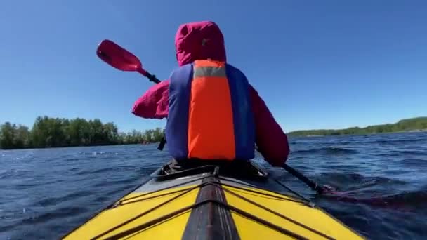 Pessoa fileiras esportes caiaque ao longo da água do lago contra o céu azul — Vídeo de Stock