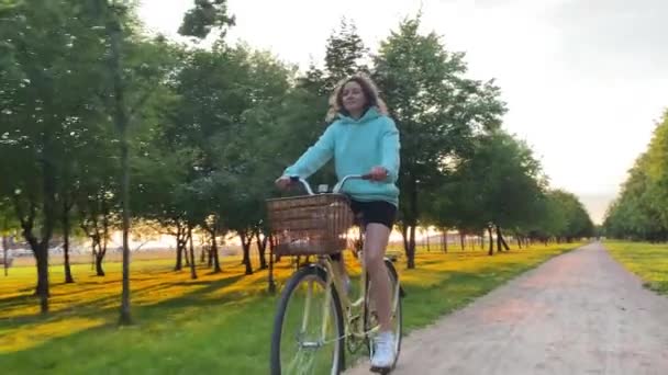 Donna con cappuccio e pantaloncini cavalca in bicicletta lungo la strada rurale — Video Stock