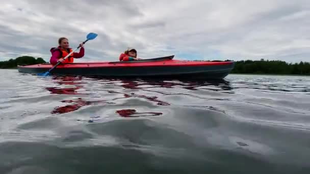Kvinna rader sport kajak med dotter längs sjön vatten — Stockvideo
