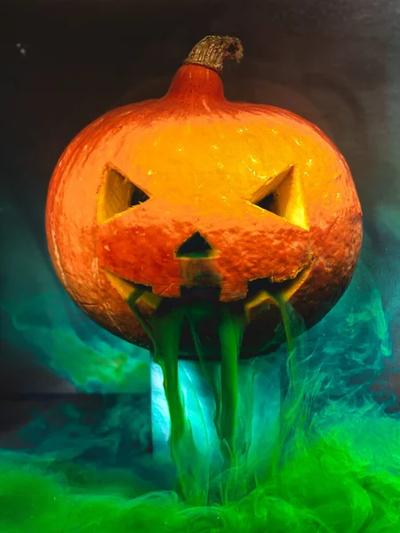 Enge Halloween pompoen in een aquarium met groene verf die uit zijn mond lekt — Stockfoto