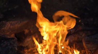 Parlak alevler gecenin karanlığında taşların yanında yanıyor.