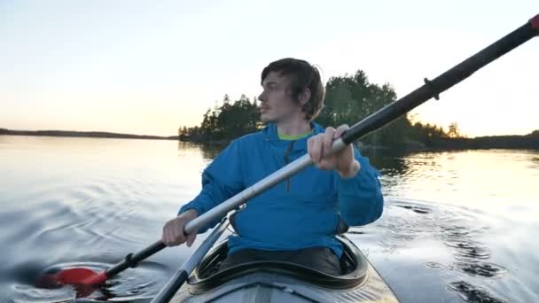 青いジャケットの男が静かな湖に沿ってスポーツカヤック — ストック動画