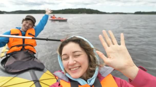 Pria dan wanita yang bahagia berlayar kayak melambaikan tangan ke kamera — Stok Video