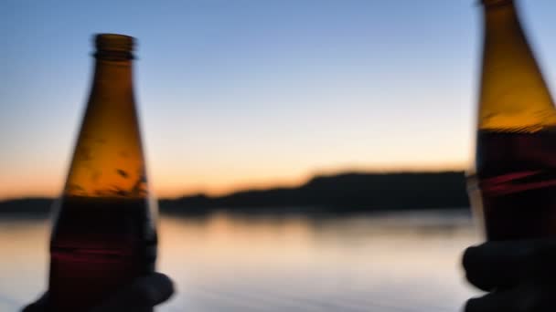 As pessoas batem garrafas de cerveja contra o rio calmo ao pôr do sol — Vídeo de Stock