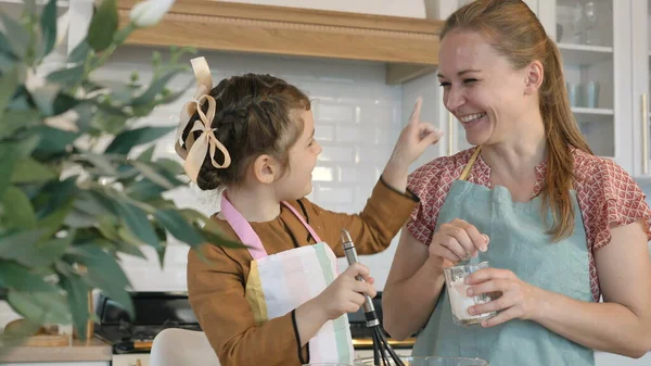 Ragazza tocca la mamma naso per dito con farina in cucina — Foto Stock