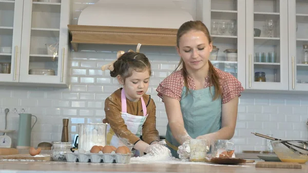 Ragazza allegra e mamma gettano farina facendo pasta in cucina — Foto Stock