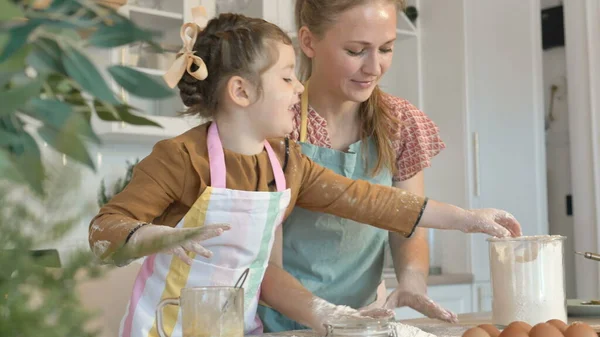 Mamma e figlia si divertono con la torta di cottura della farina a tavola — Foto Stock