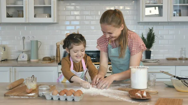 La figlia versa la farina su tavolo di legno da tazza per cucinare la torta — Foto Stock