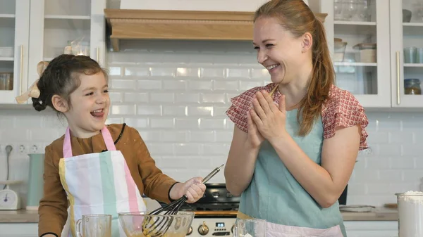 Bambina e madre giocano con la farina cucinando gustosa torta — Foto Stock