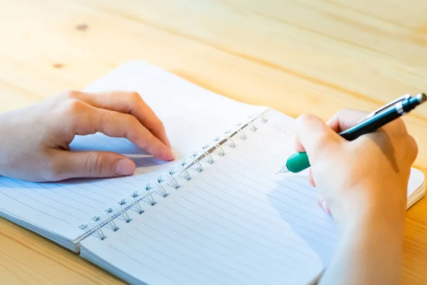 Vrouwelijke hand met potlood schrijven op notebook bij Coffee Shop. vrouw — Stockfoto